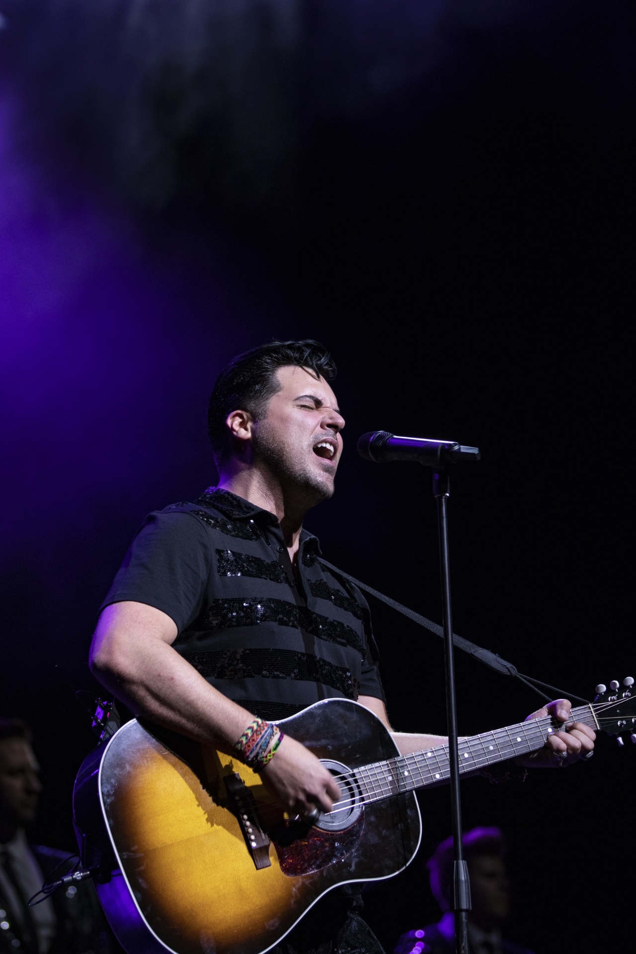 Vocalist mid-performance with acoustic guitar
