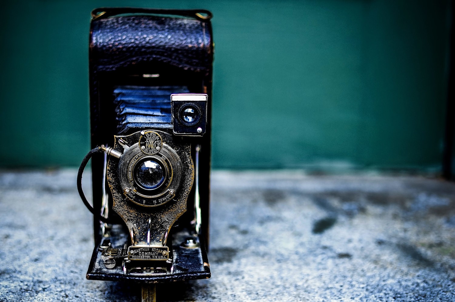 Vintage folding camera against a teal wall